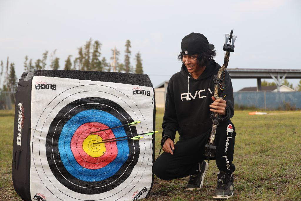 Proud youth kneeling beside bullseye target